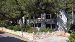 a white building with a stone wall and trees at Apartments Vera - Mirca in Mirce