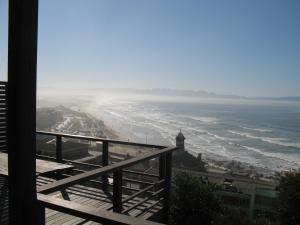 a view of the beach from the balcony of a building at Seaview Apartment in Muizenberg in Muizenberg