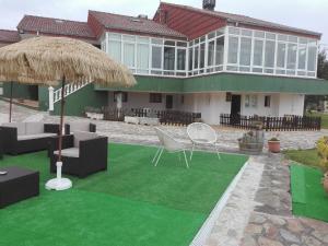 a house with a green lawn with chairs and umbrellas at Alojamientos el Paramo in San Vicente de la Barquera