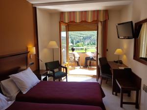 a hotel room with a bed and a desk and a window at Hotel Turmo in Labuerda