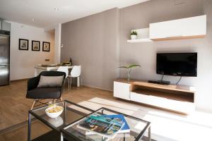 un salon avec une table en verre et une télévision dans l'établissement Feelathome Mozart Apartments, à Barcelone