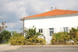 a white building with an orange roof next to a street at Le grenier a sel in Marennes
