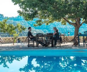 a man and woman sitting at a table by a pool at Petropoulakis Tower in Gythio