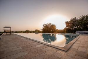 a swimming pool with a chair on a patio at Agriturismo Le Chiuse di Guadagna in Scicli