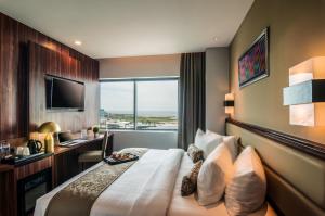 una camera d'albergo con letto, scrivania e TV di Arthama Hotels Makassar a Makassar