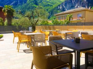 a patio with tables and chairs and mountains in the background at GardaBreak Rooms&Breakfast Holiday Apartments in Riva del Garda