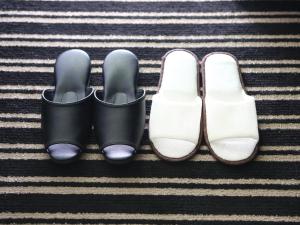 une paire de chaussures noires et une paire de chaussures blanches dans l'établissement APA Hotel Nishi-Azabu, à Tokyo