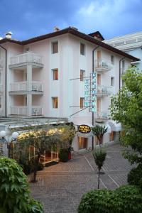 een groot wit gebouw met een bord ervoor bij Hotel Abbazia in Grado
