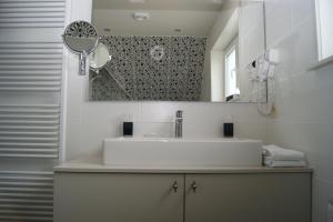 a white bathroom with a sink and a mirror at Hotel Les Arcades in Knokke-Heist