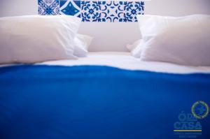 uma cama com almofadas brancas e azul e branco em Ó da Casa em Peniche