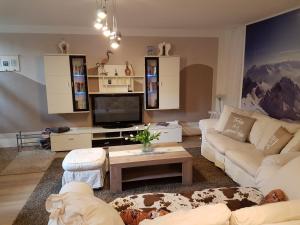 a living room with white couches and a tv at Haus Valder in Niedernsill