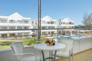 uma varanda com mesa e cadeiras e uma piscina em Apartamentos Habitat em Port de Pollensa