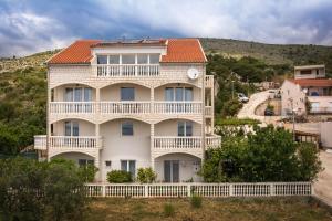 duży biały dom z pomarańczowym dachem w obiekcie Apartments Ilak w Trogirze