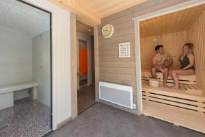 a man and a woman sitting in a sauna at Les Carmes and spa in Le Thor