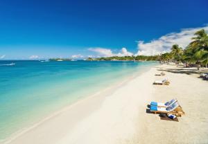 a beach with two lounge chairs and the ocean at Sandals Negril Beach All Inclusive Resort and Spa - Couples Only in Negril