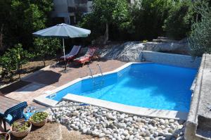 una piscina con sombrilla, 2 sillas y una mesa en Villa Donna, en Trogir