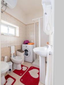 ein Badezimmer mit einem weißen Waschbecken und einem roten Teppich in der Unterkunft Appartamento ad uso Turistico Trapani One in Trapani