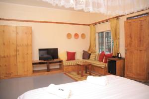 a bedroom with a bed and a tv and a couch at Kampala Forest Resort - KFR Lodge in Kampala