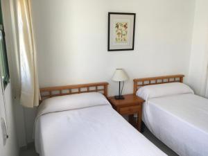 a room with two beds and a table with a lamp at Apartamentos Torrelaguna in Vera