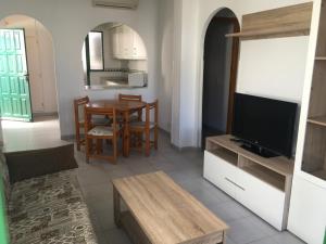 a living room with a television and a dining room at Apartamentos Torrelaguna in Vera