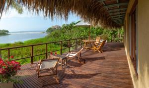a deck with chairs and a table with a view of the water at Villa Playa Tayrona, Los Naranjos in Los Naranjos
