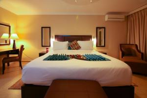 a bedroom with a large white bed with a desk at Best Western Plus Accra Beach Hotel in Teshi