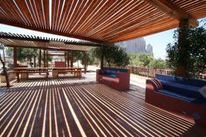 a wooden deck with benches and a picnic table at Baglio Del Sole in San Vito lo Capo