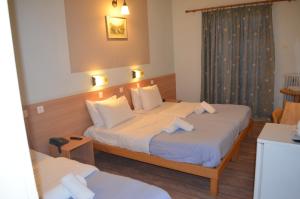 Cette chambre comprend 2 lits et une fenêtre. dans l'établissement Rozos Hotel, à Porto Heli