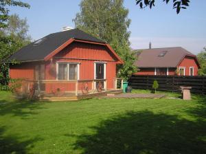 een rood huis met een zwart dak in een tuin bij Teeny in Pärnu