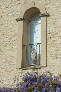 a window with a statue on a balcony at Les Carmes and spa in Le Thor