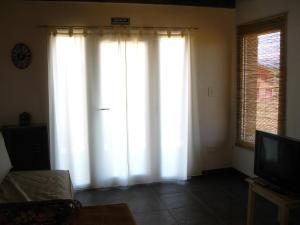 sala de estar con cortinas blancas y TV en Morada al Sur en Dina Huapi