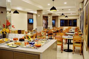 restauracja ze stołami i krzesłami z jedzeniem w obiekcie Brumado Hotel w mieście Campo Grande