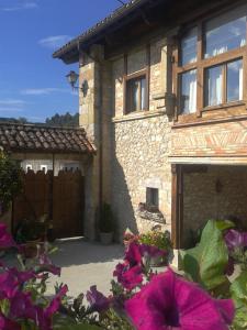 una casa de piedra con una puerta y flores púrpuras en Posada El Salin, en Muñorrodero