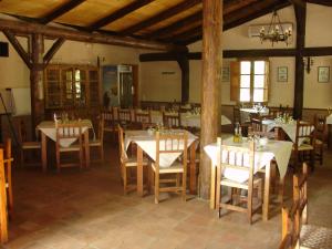 Un comedor con mesas y sillas blancas. en Camping Rural Llanos de Arance, en Coto Ríos