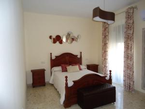 sypialnia z dużym drewnianym łóżkiem i oknem w obiekcie Apartamentos Acevedo Centro w mieście Ronda