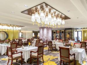 Un comedor con mesas y sillas y una lámpara de araña. en Wanda Vista Beijing, en Beijing
