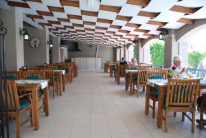 a restaurant with wooden tables and chairs and people sitting at tables at Ant Apart Hotel in Oludeniz