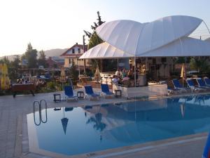 a swimming pool with blue chairs and a white umbrella at Ant Apart Hotel in Oludeniz