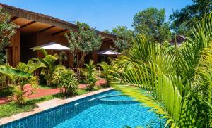 a swimming pool in front of a house with palm trees at Sok Sabay Resort in Sihanoukville