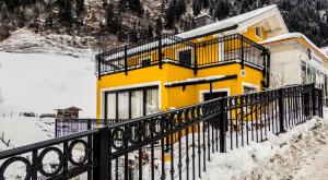 um edifício amarelo com uma cerca preta na neve em Villa Gastuna em Bad Gastein
