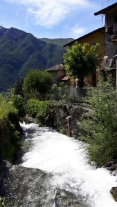 a stream of water with a house and mountains at La Turr De Mezz in Nesso