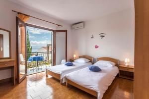 two beds in a room with a balcony at Apartmani Bezma in Bol