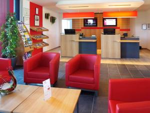 una sala d'attesa con sedie rosse in un negozio di ibis Bulle - La Gruyère a Bulle