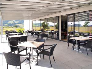 布勒ibis Bulle - La Gruyère Swiss Bike Hotel的有桌椅和窗户的餐厅