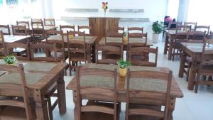 Cette chambre dispose de tables en bois, de chaises et de fleurs. dans l'établissement Pousada Peruíbe Ametista, à Peruíbe