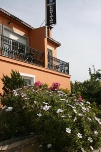 un bâtiment avec des fleurs roses et blanches devant lui dans l'établissement Hostal Pereiriña, à Cee