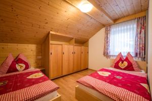 2 letti in una camera con pareti in legno e pavimenti in parquet di Ferienwohnung Spindlegger a Schlitters