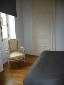 a bedroom with a chair and a door at Les Charmottes in Nuits-Saint-Georges