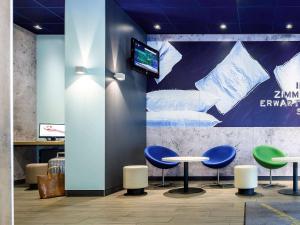 a lobby with two tables and a tv on a wall at Ibis budget München Airport Erding in Erding