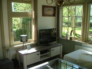 a living room with a tv and two windows at B&B Saense huisje in Assendelft